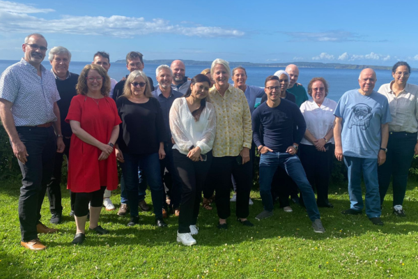 Consortium Members gather on a beautiful green cliff with ocean in background in Northern Ireland