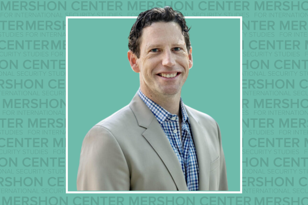 Photo of Chris Nichols in a tan suit on a teal background with repeating Mershon Center text.