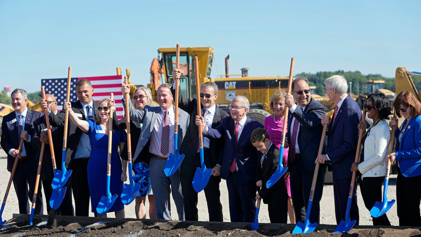 People smiling with shovels at construction site