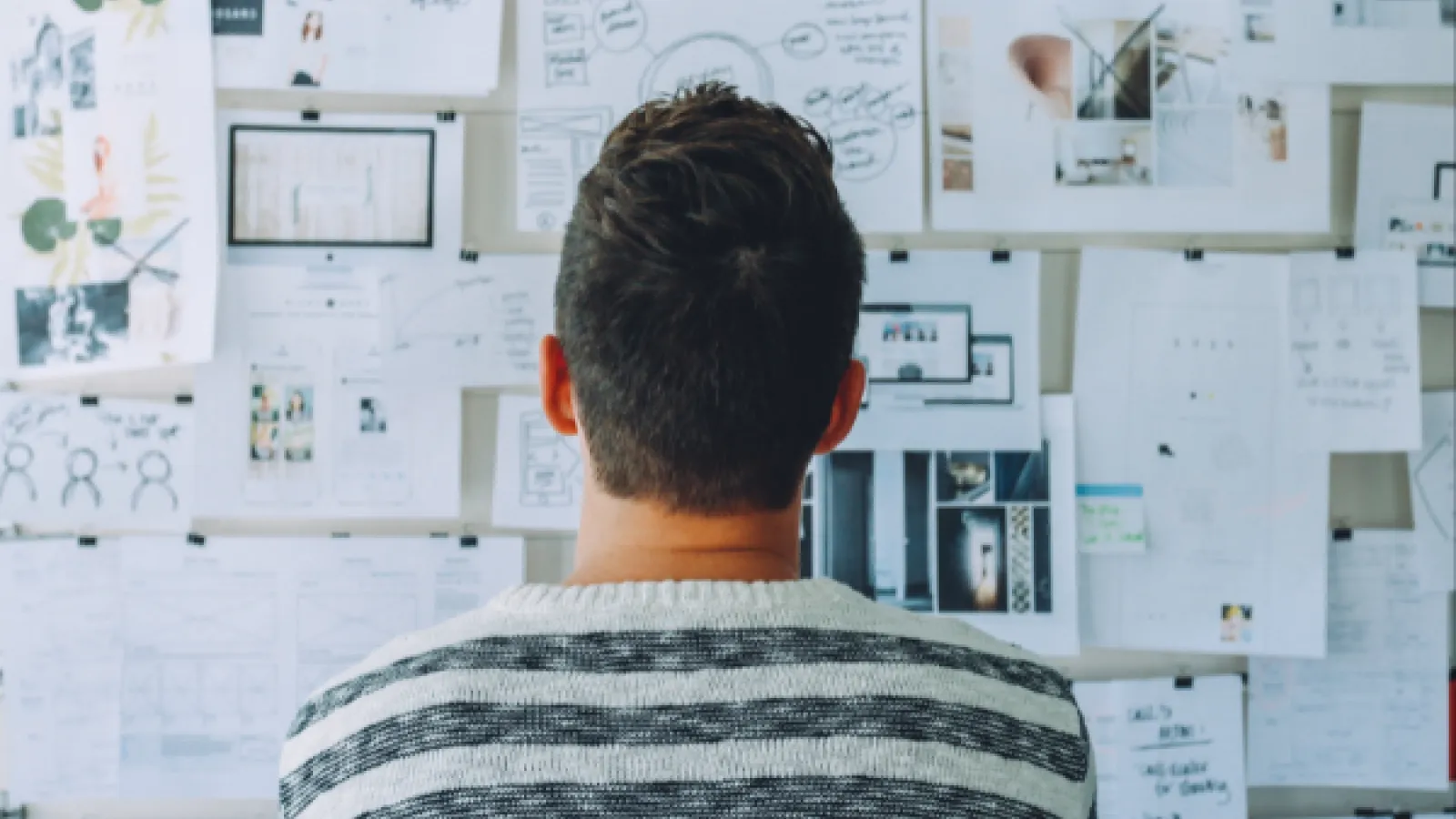 person thinking in front of board full of notes