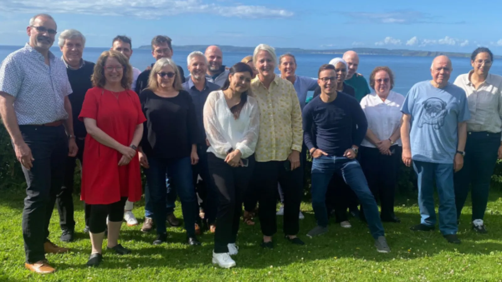 Consortium Members gather on a beautiful green cliff with ocean in background in Northern Ireland