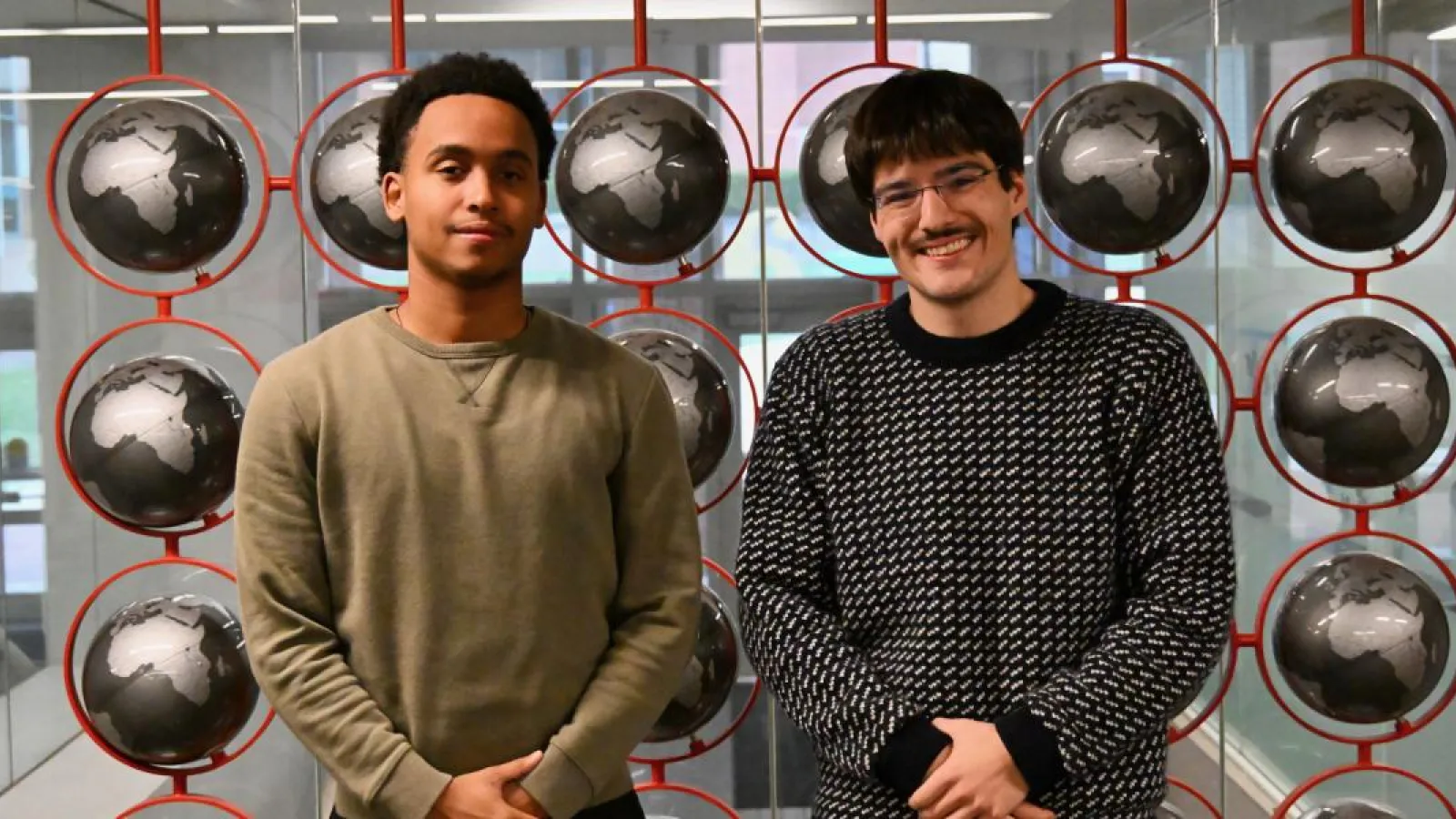 Two students pose in front of globes 