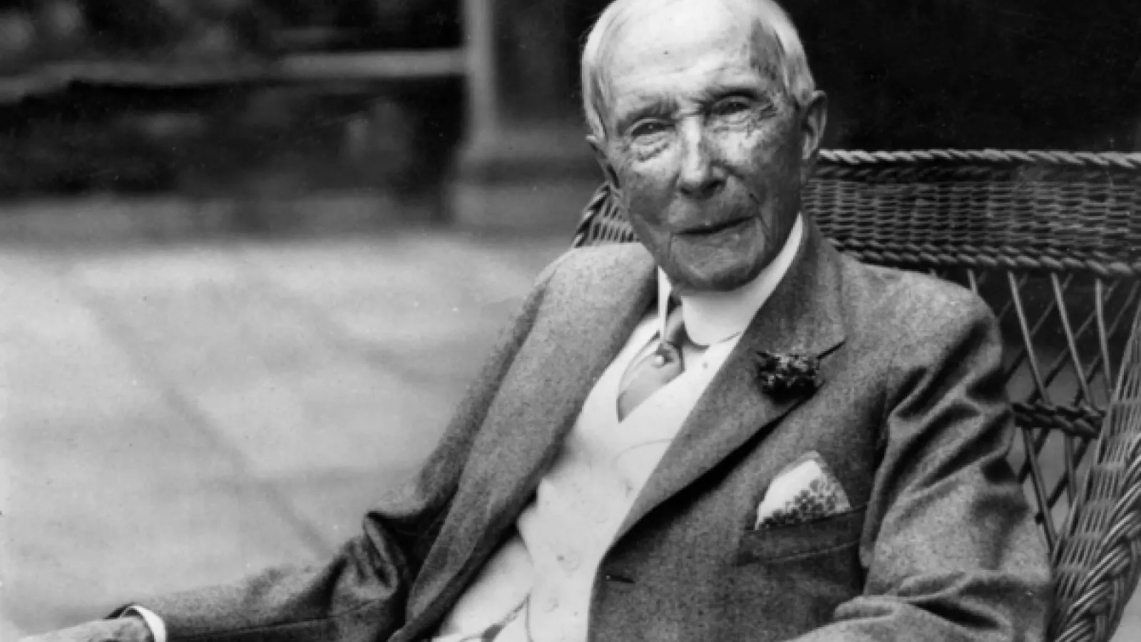 Old man sitting in rattan chair in 3 piece suit