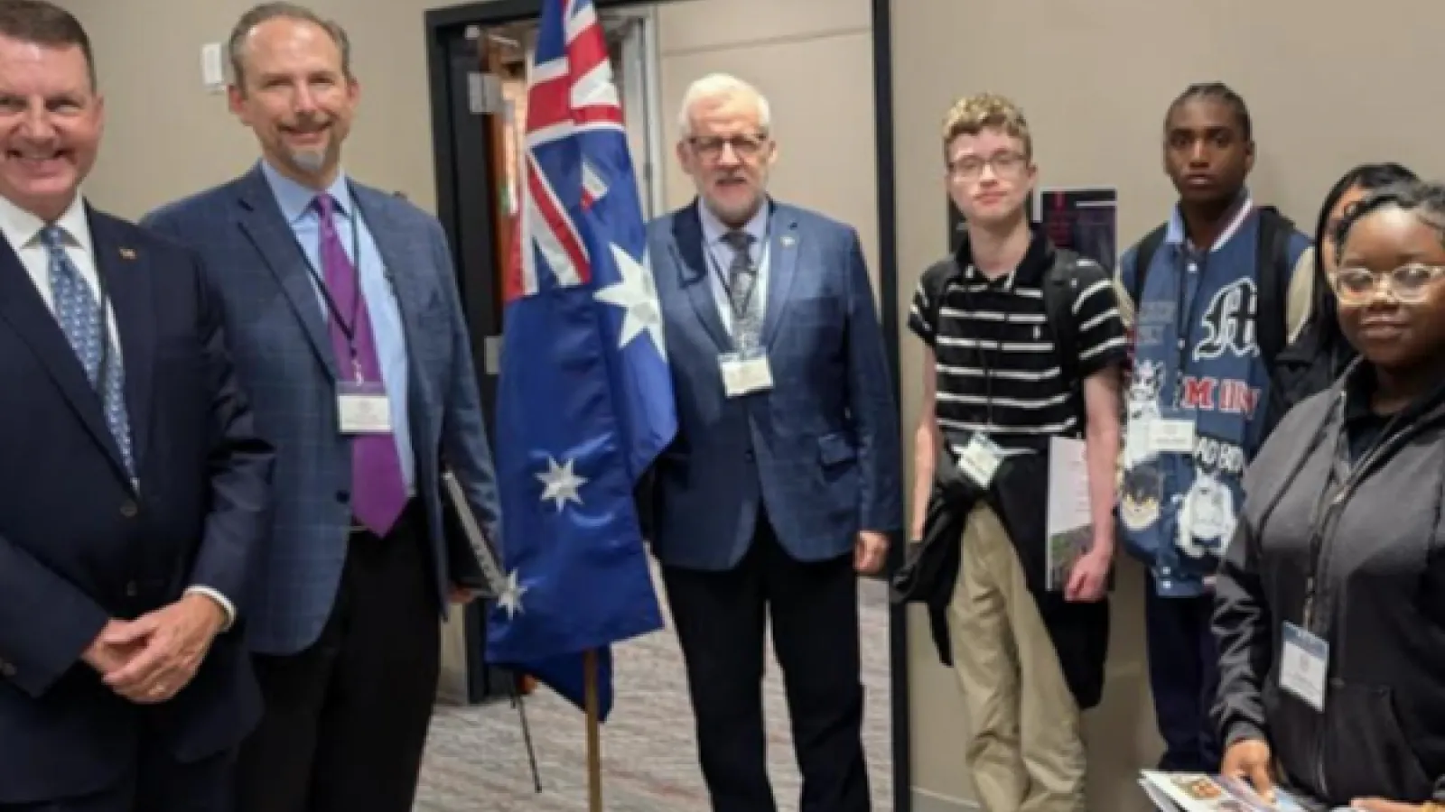 3 white men and 3 teenagers stand next to Australian flag