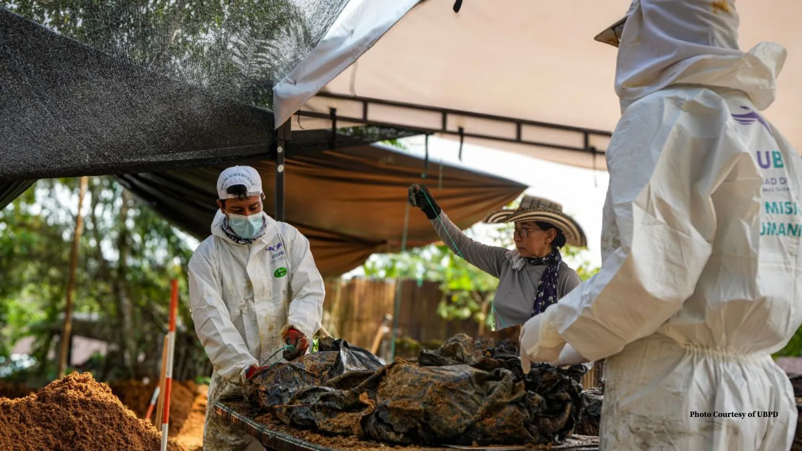Forensic scientists in white scrubs exhuming remains