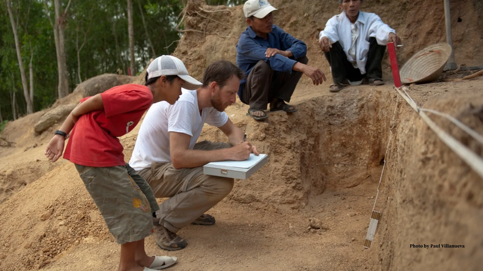 Derek Congram collecting soil samples with a group of children