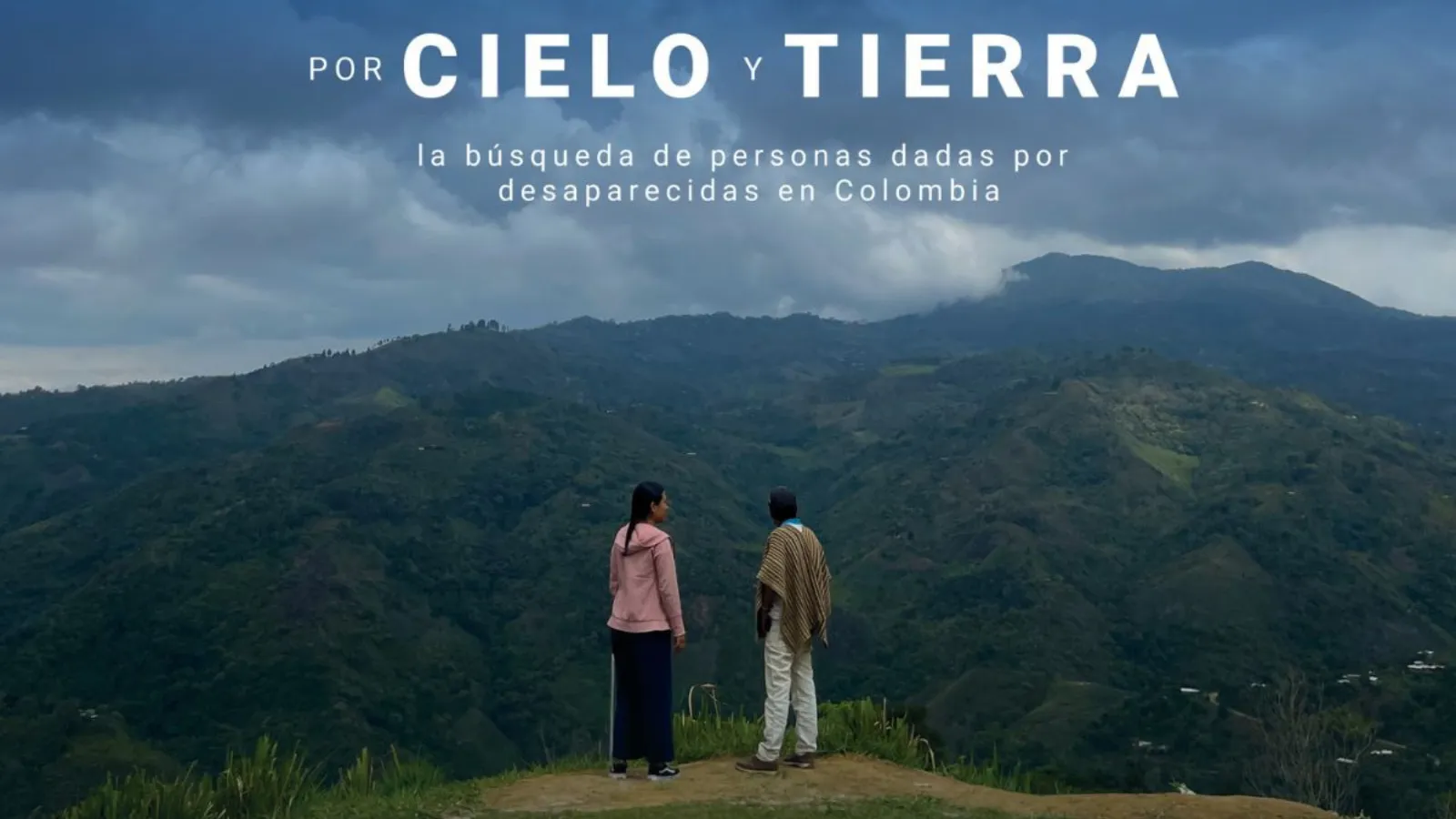 Two people on a hill with mountains in the background