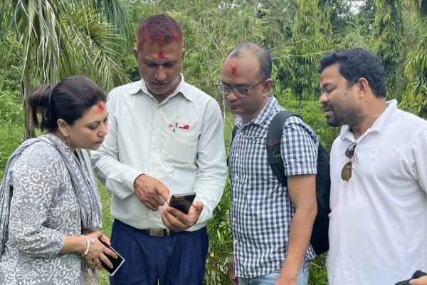 Four scholars in the field standing next to each other looking at data on phone