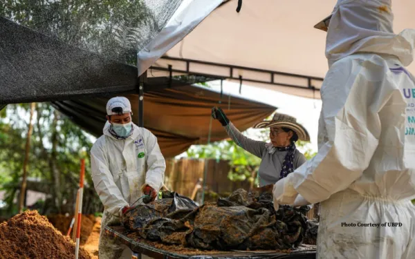 Forensic scientists in white scrubs exhuming remains