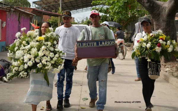 Family members carrying small coffin and flowers during burial ritual for a disappeared loved one