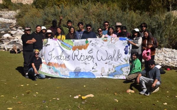 People holding sign reading Indus River Walk