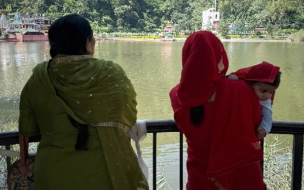 Two women and a baby looking out at Rewalsar Lake