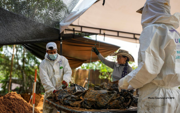 Forensic scientists in white scrubs exhuming remains