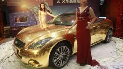 Expensive gold car with women in dressers standing next to it