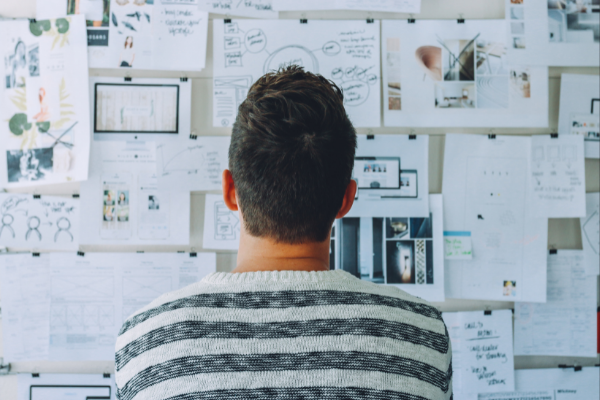 person thinking in front of board full of notes