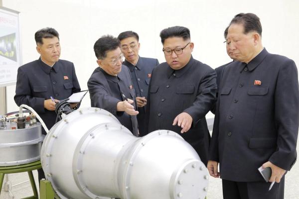 Kim Jong-Un looking at a nuclear warhead with military officials