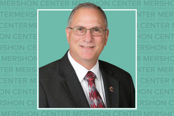 Photo of Peter Mansoor in a suit with a teal background that repeats the word Mershon Center.