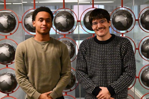 Two students pose in front of globes 