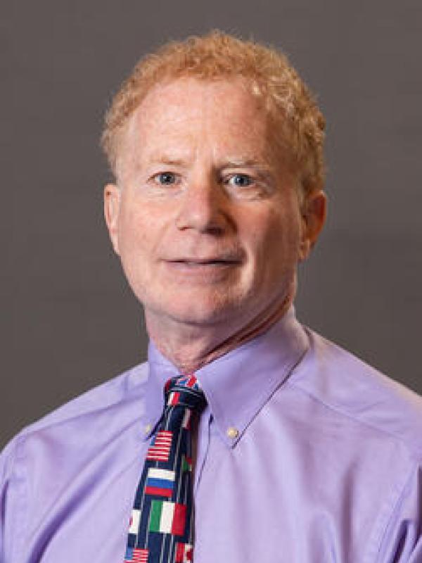 Mitchell Lerner in a purple dress shirt wearing a tie with the flags of the world on it. 