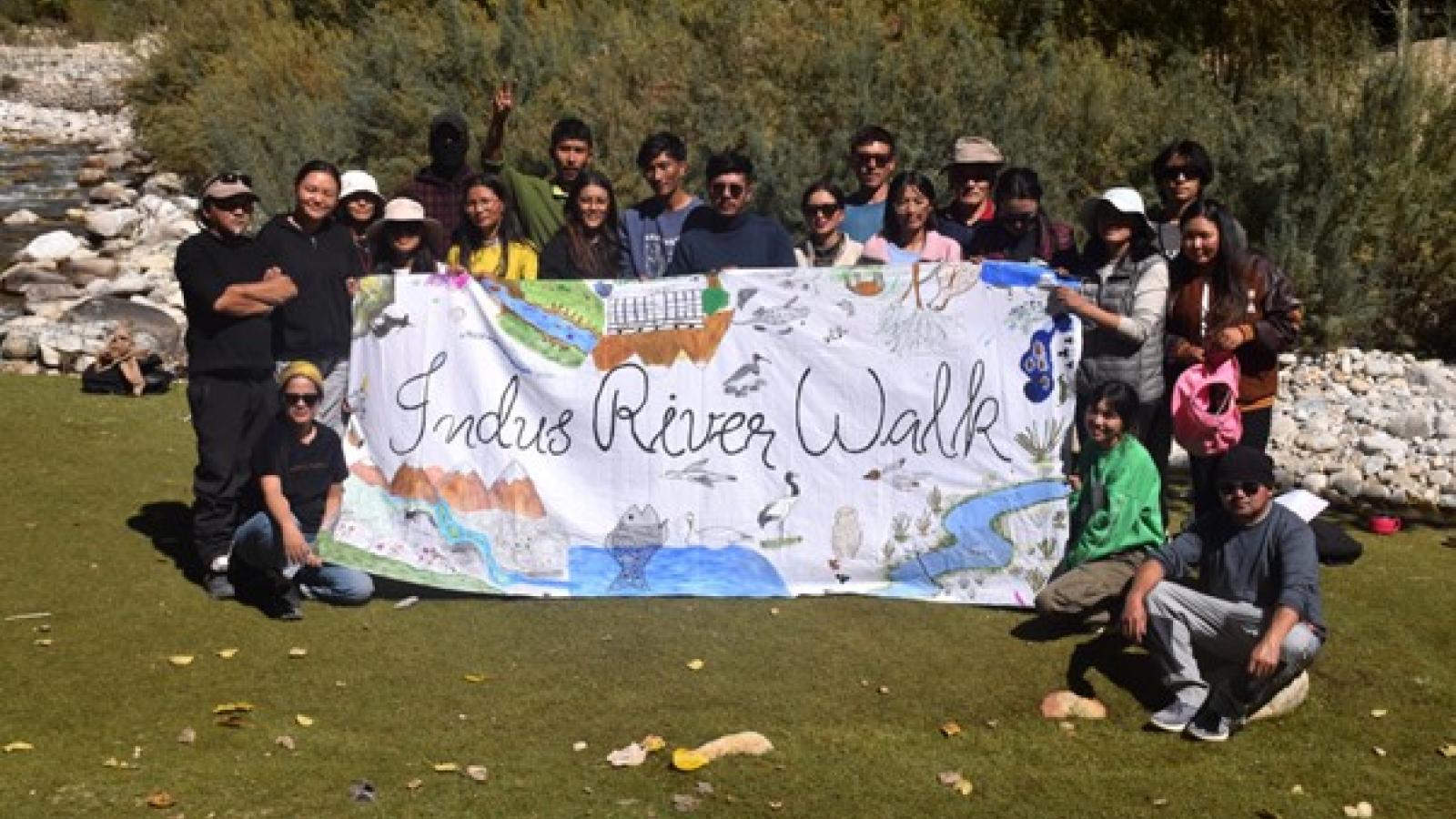 People holding sign reading Indus River Walk